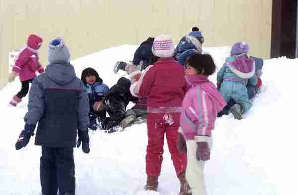 Group of children playing in snow bank.