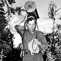 Josiah McCleod, packing a tent and supplies, walking through the bush